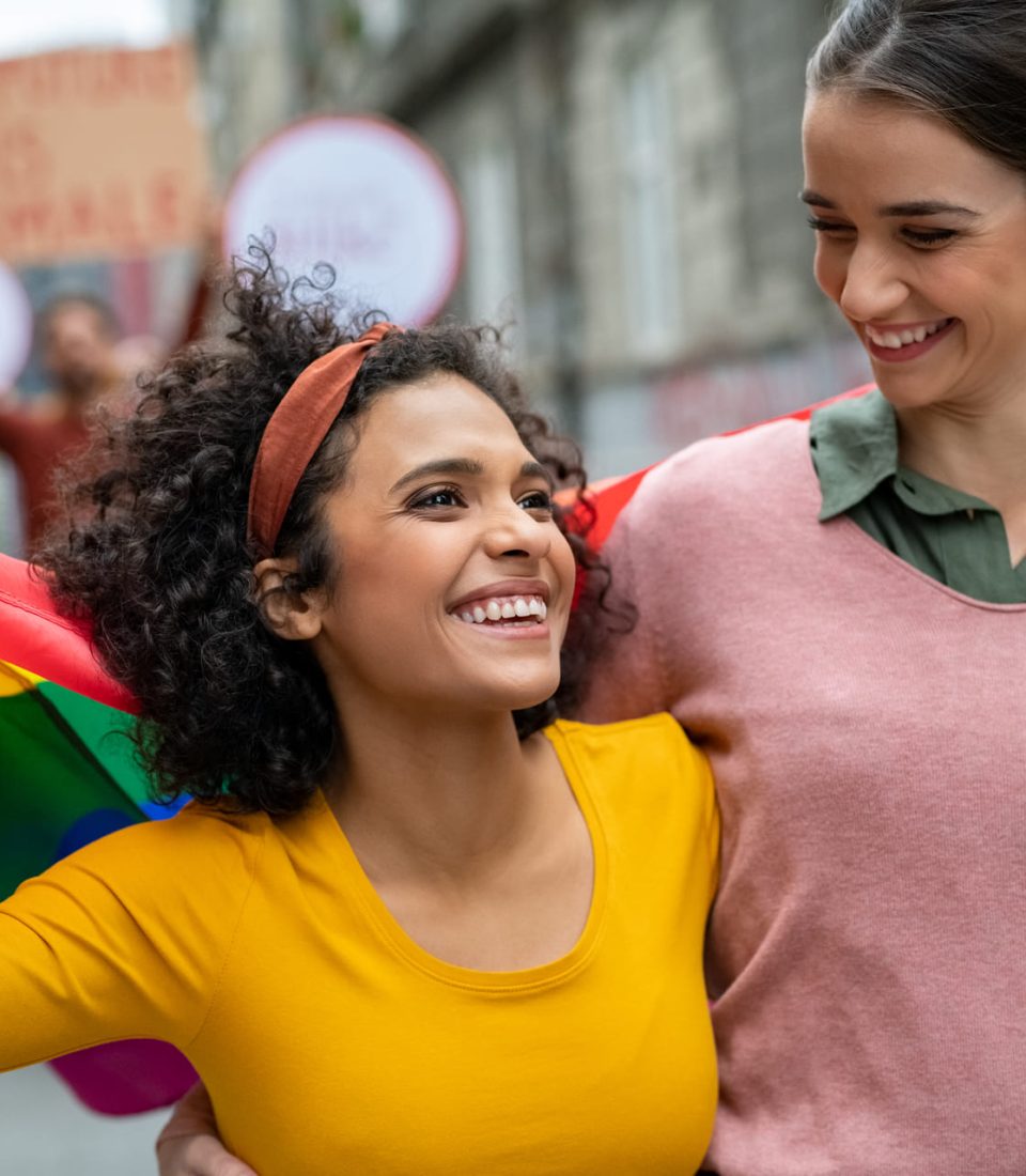 lesbian-couple-at-gay-pride-with-rainbow-flag-EM4Y9P9.jpg